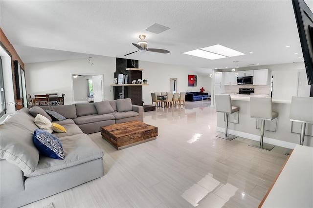 living area featuring a skylight, a ceiling fan, recessed lighting, and a textured ceiling
