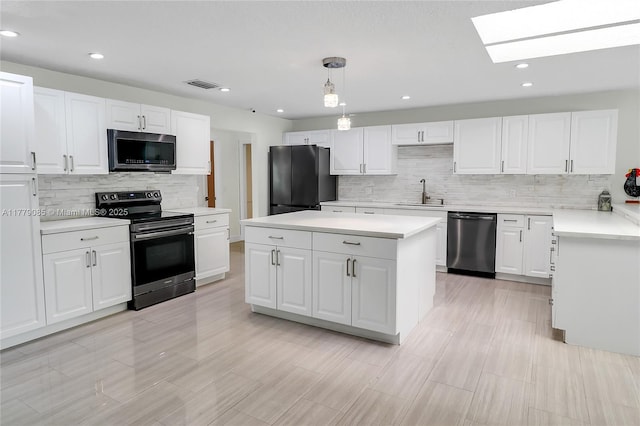 kitchen featuring white cabinets, a skylight, appliances with stainless steel finishes, a sink, and light countertops