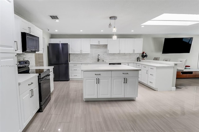 kitchen with white cabinets, a sink, light countertops, a peninsula, and black appliances