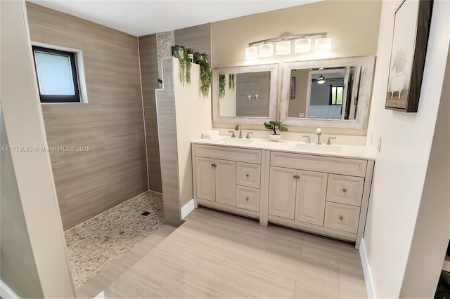 bathroom with ceiling fan, double vanity, a sink, and walk in shower