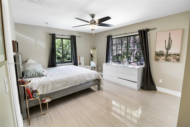 bedroom with a textured ceiling, ceiling fan, and baseboards