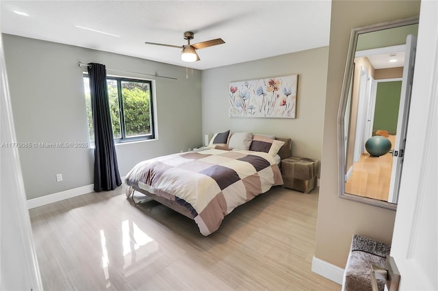 bedroom with light wood finished floors, baseboards, and a ceiling fan