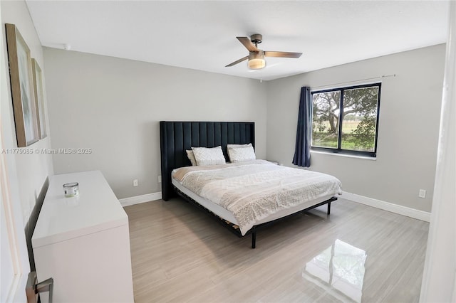bedroom with light wood-type flooring, ceiling fan, and baseboards