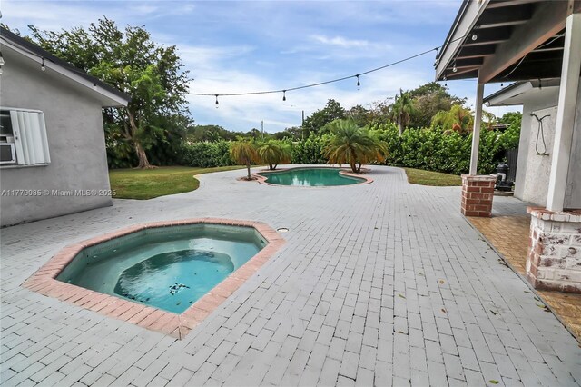 view of swimming pool featuring a patio area, a fenced in pool, and an in ground hot tub