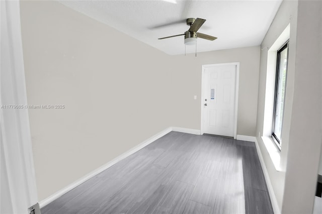 spare room featuring dark wood-style flooring, baseboards, and ceiling fan