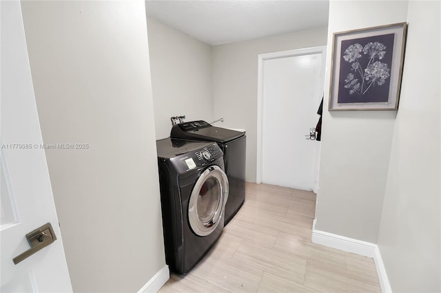 washroom featuring laundry area, separate washer and dryer, and baseboards