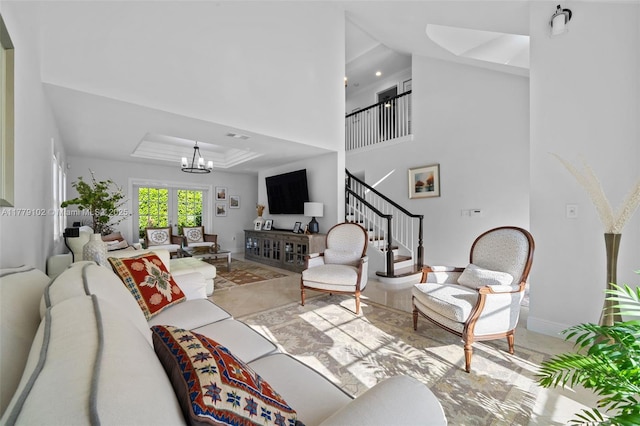 living room with a towering ceiling, baseboards, an inviting chandelier, stairway, and a tray ceiling
