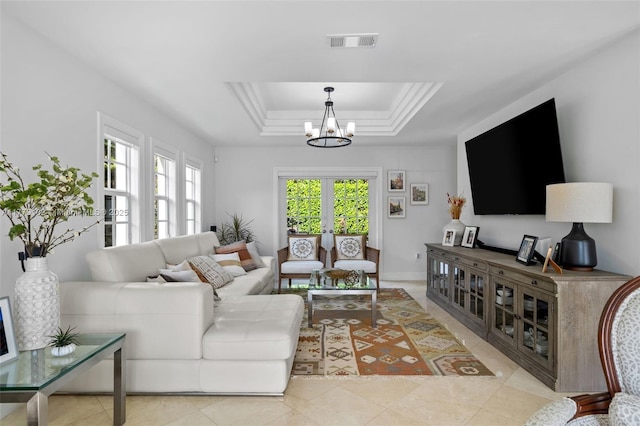 living room featuring tile patterned flooring, visible vents, a tray ceiling, and an inviting chandelier