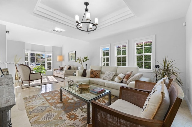 living area with a tray ceiling, a healthy amount of sunlight, an inviting chandelier, and visible vents