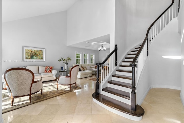 stairs with a chandelier, a high ceiling, and baseboards