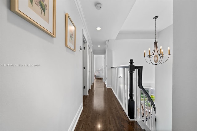 hall featuring baseboards, an inviting chandelier, ornamental molding, dark wood finished floors, and recessed lighting