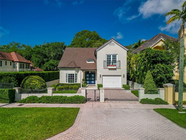 view of front of house with a fenced front yard, stucco siding, decorative driveway, a gate, and an attached garage