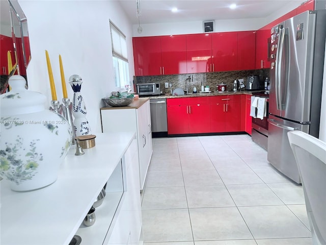 13255 SW 7th Ct Unit 401D, Pembroke Pines, FL 33027 - kitchen featuring red cabinets, appliances with stainless steel finishes, tasteful backsplash, a sink, and light tile patterned floors