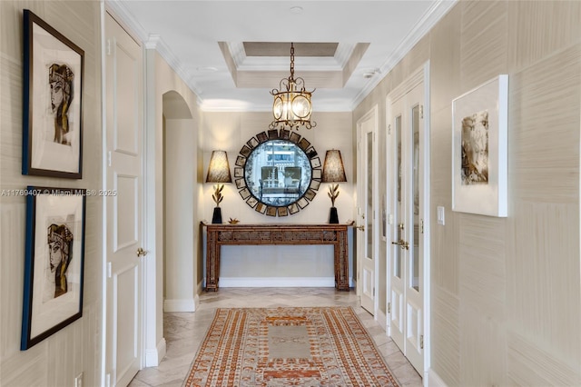 corridor with french doors, arched walkways, a raised ceiling, a notable chandelier, and ornamental molding