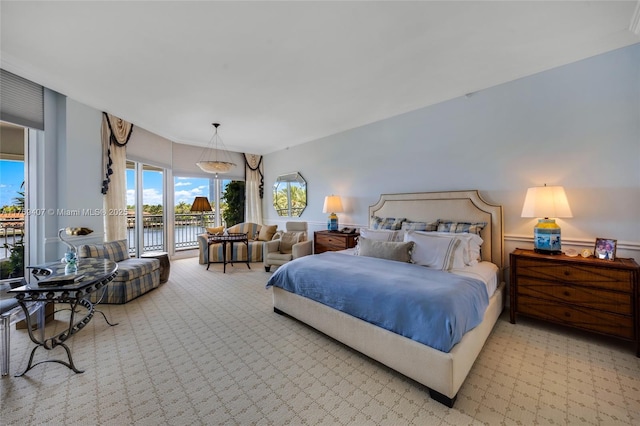 bedroom with a water view, light colored carpet, and access to exterior