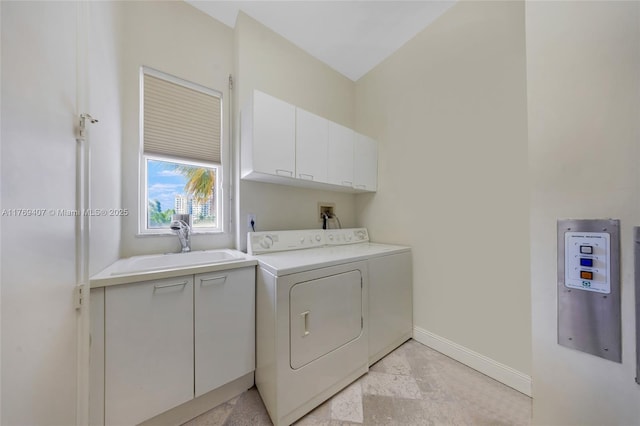 laundry room featuring cabinet space, baseboards, washing machine and dryer, and a sink