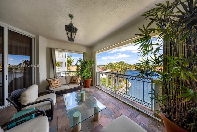 exterior space featuring a textured ceiling, a water view, and stone tile flooring