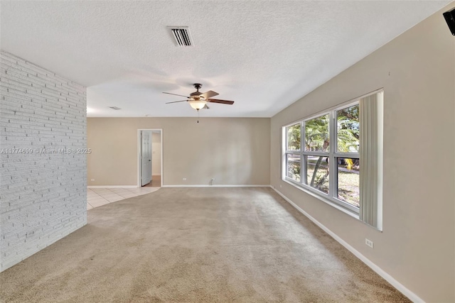 spare room featuring visible vents, baseboards, a ceiling fan, a textured ceiling, and light colored carpet