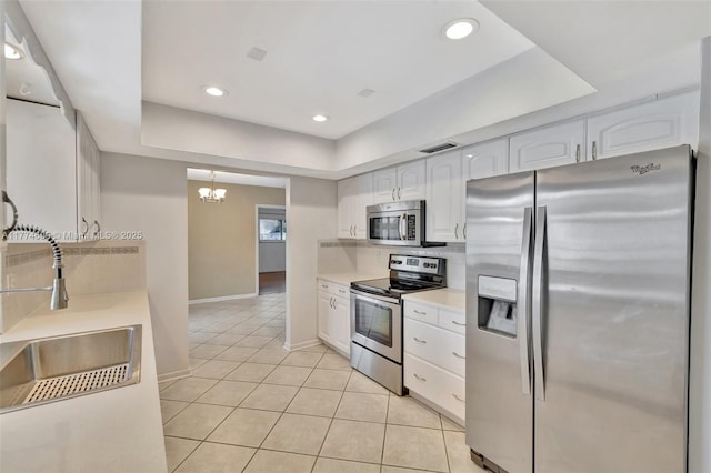 kitchen with tasteful backsplash, a chandelier, light countertops, white cabinets, and stainless steel appliances