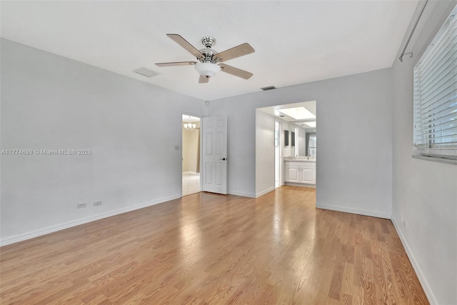 interior space with connected bathroom, a ceiling fan, visible vents, light wood finished floors, and baseboards