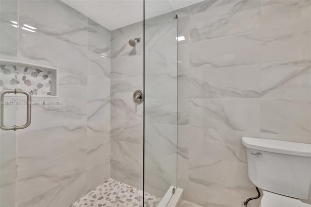 bathroom featuring a marble finish shower and toilet