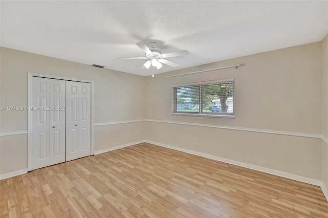 unfurnished bedroom with a closet, a ceiling fan, visible vents, light wood finished floors, and baseboards