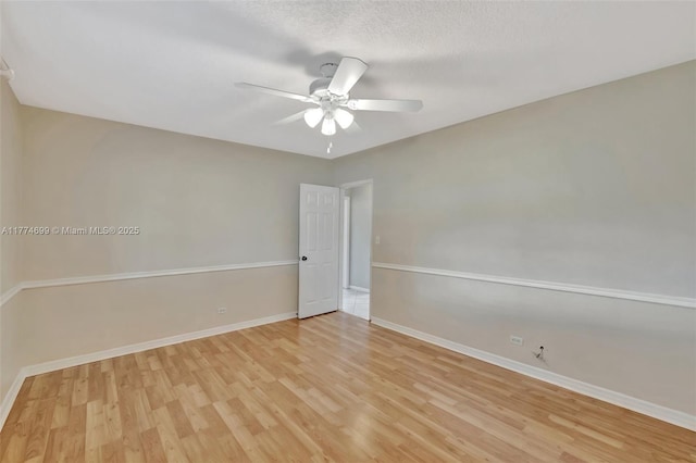 spare room featuring ceiling fan, a textured ceiling, light wood-style floors, and baseboards