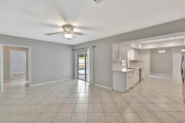 kitchen with light tile patterned floors, light countertops, white cabinetry, and ceiling fan with notable chandelier