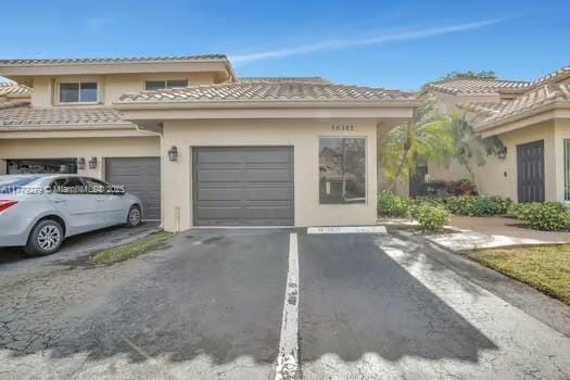view of front of home featuring a garage, driveway, stucco siding, and a tile roof