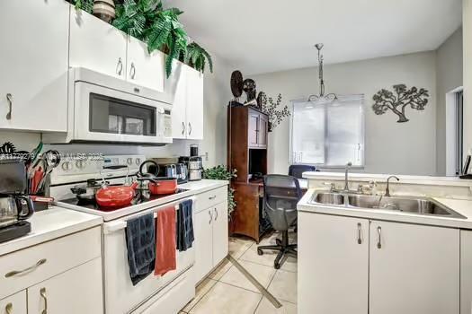 kitchen featuring white cabinets, light tile patterned floors, a sink, and white electric range oven