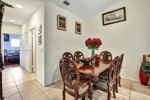 dining room with lofted ceiling, visible vents, and light tile patterned flooring