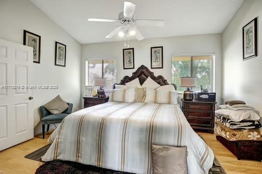 bedroom featuring a ceiling fan, light wood-style flooring, multiple windows, and lofted ceiling