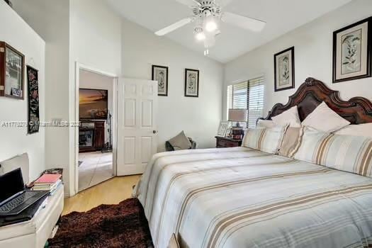 bedroom with a ceiling fan, wood finished floors, and lofted ceiling