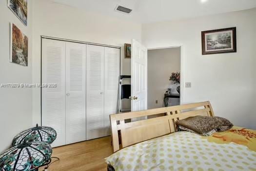 bedroom featuring visible vents, a closet, and wood finished floors