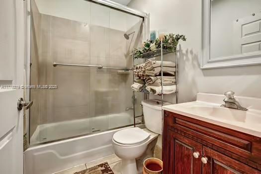 full bath with bath / shower combo with glass door, vanity, and toilet