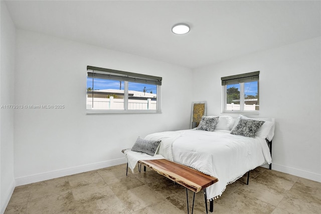 bedroom with stone finish floor, baseboards, and multiple windows