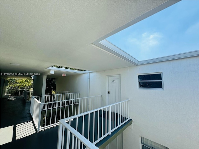 view of exterior entry featuring a balcony and stucco siding
