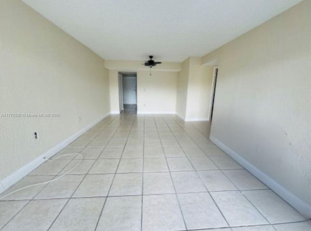 empty room featuring baseboards and light tile patterned flooring