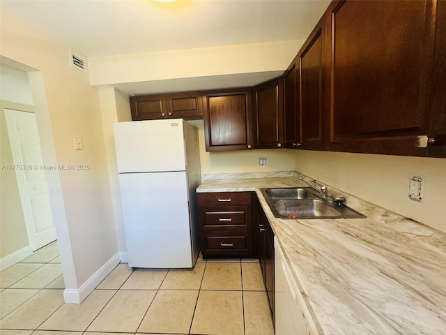 kitchen featuring visible vents, a sink, light countertops, freestanding refrigerator, and light tile patterned flooring