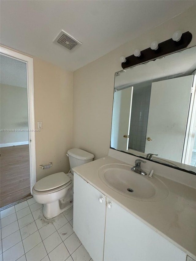 bathroom with toilet, vanity, and visible vents