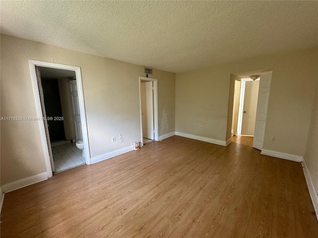 unfurnished room with visible vents, baseboards, light wood finished floors, and a textured ceiling