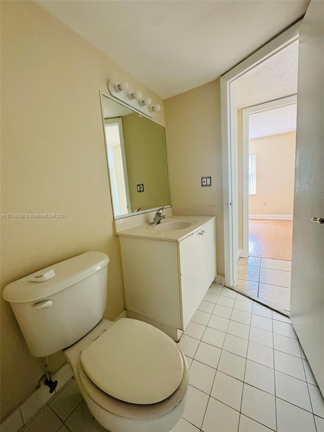 bathroom with toilet, tile patterned floors, vanity, and baseboards