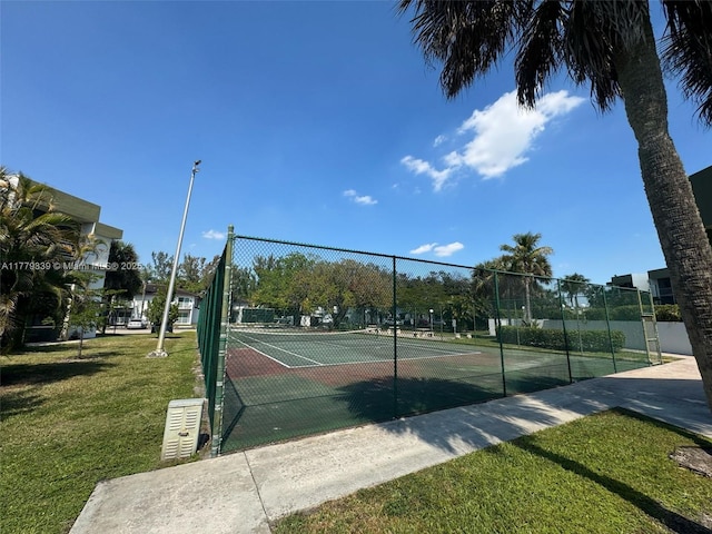 view of tennis court featuring fence and a lawn