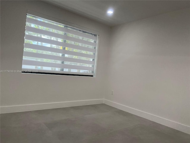 spare room with concrete floors, baseboards, and recessed lighting