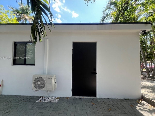 doorway to property with ac unit, a patio area, and stucco siding