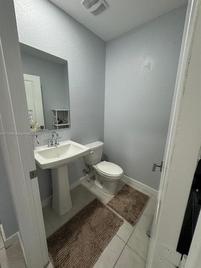 bathroom featuring baseboards, tile patterned flooring, toilet, visible vents, and a sink