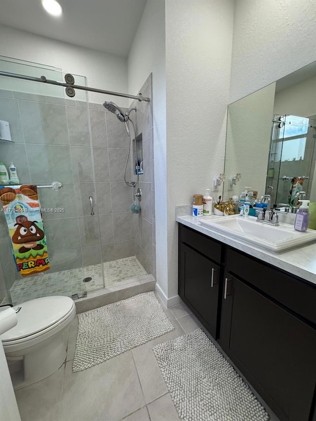 bathroom with toilet, vanity, a shower stall, and tile patterned flooring