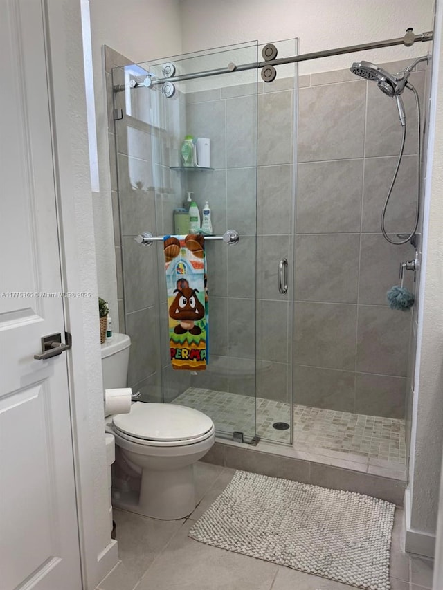 bathroom featuring toilet, a stall shower, and tile patterned flooring