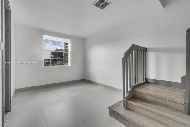 stairway with tile patterned floors, visible vents, and baseboards