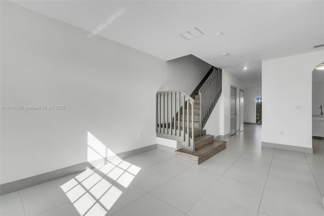 stairway featuring tile patterned floors, visible vents, and baseboards